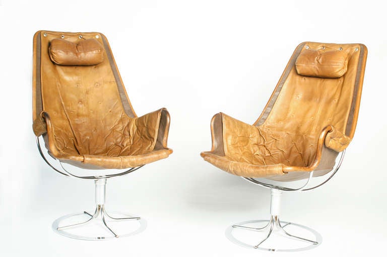 Two iconic Bruno Mathsson Jetson chairs. These are the later models with the armrests in their original leather backed by cloth in a nylon mesh sling.