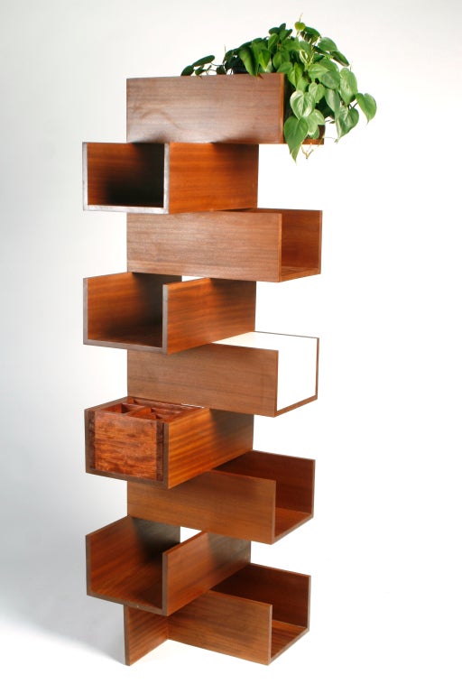 Corner bookcase designed to maximize storage and space options in urban settings. Custom sizing, finishes, and accessories available. As shown: includes bubinga organizer box, winge planter and light box.