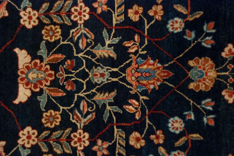 An antique, late 19th century, Persian Mohajeran Sarouk rug with beautiful mirrored tree-of-life pattern on a deep indigo background surrounded by a contrasting crimson floral border.