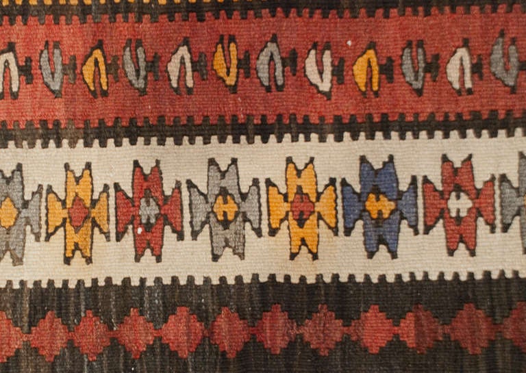 An early 20th century Persian Zarand Kilim runner with beautiful variegated red wool background with multiple contrasting geometric patter borders.