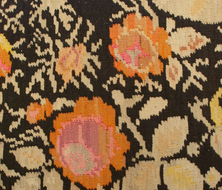 Un antico tappeto Karabakh Kilim persiano dell'inizio del XX secolo con un bellissimo e audace motivo floreale circondato da un bordo floreale asimmetrico complementare, tessuto in tenui colori pastello su sfondo nero.