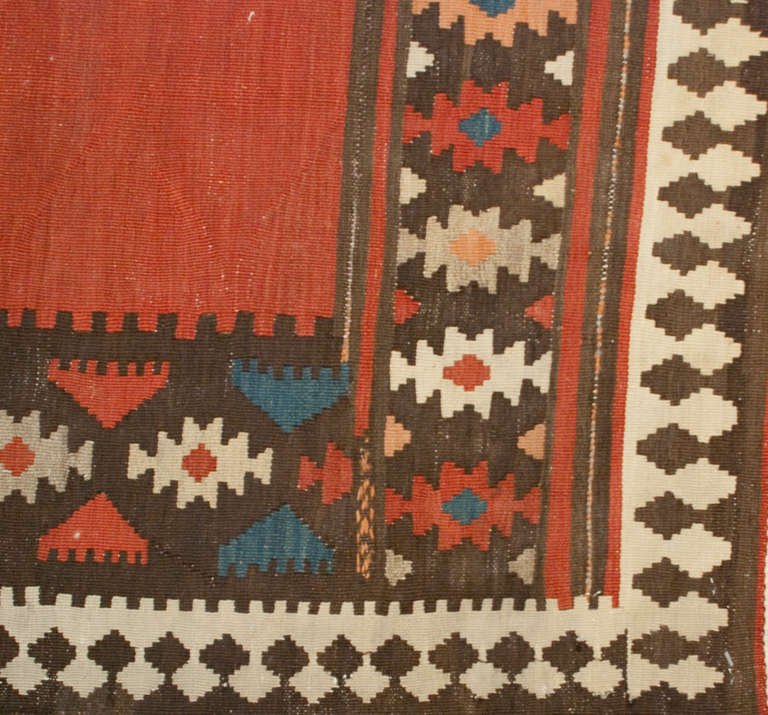 A late 19th century Persian Shirvan kilim runner with a central crimson field surrounded by a wonderful geometric border.