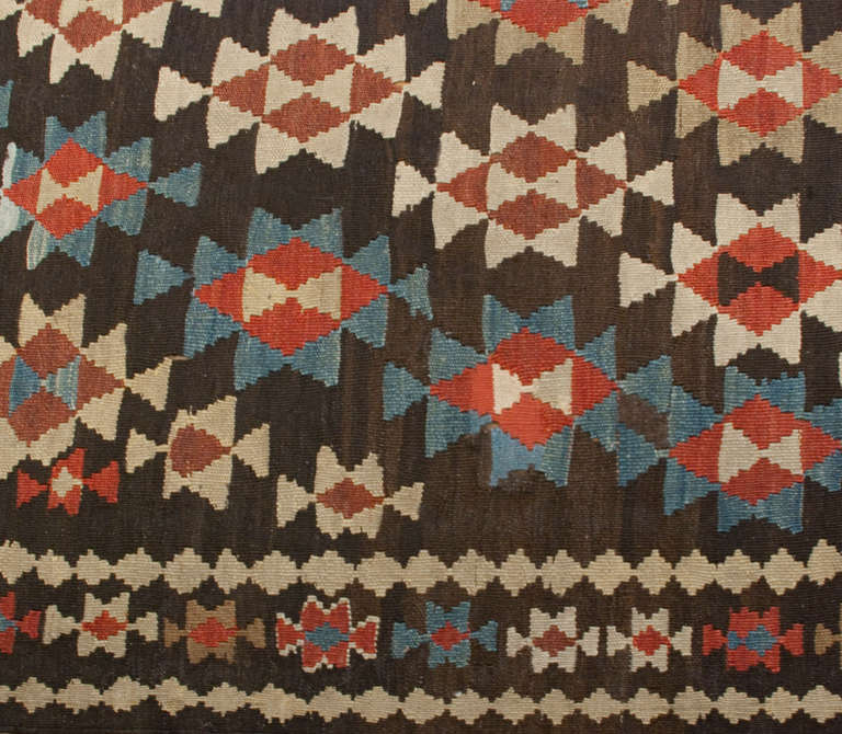 An early 20th century Persian Varamin Kilim runner with all-over multicolored geometric floral pattern surrounded by multiple complementary borders.