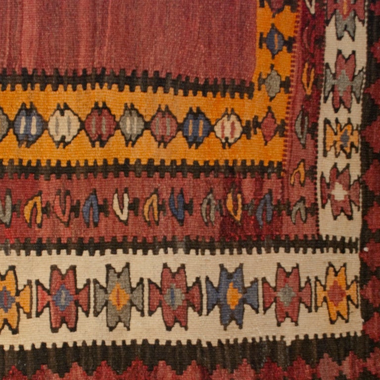 An early 20th century Persian Zarand Kilim carpet runner with variegated red central field surrounded by contrasting and alternating geometric patterned borders.

Measures: 3.10