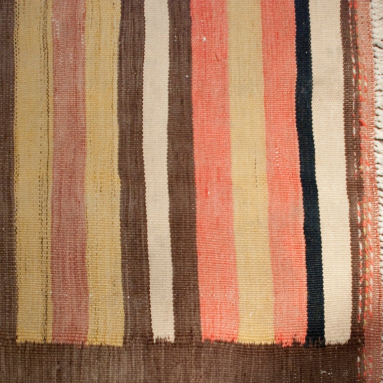 An early 20th century Persian Zarand Kilim carpet with alternating red, yellow, white, brown and indigo stripes, with a brown border.

Measures: 3'4