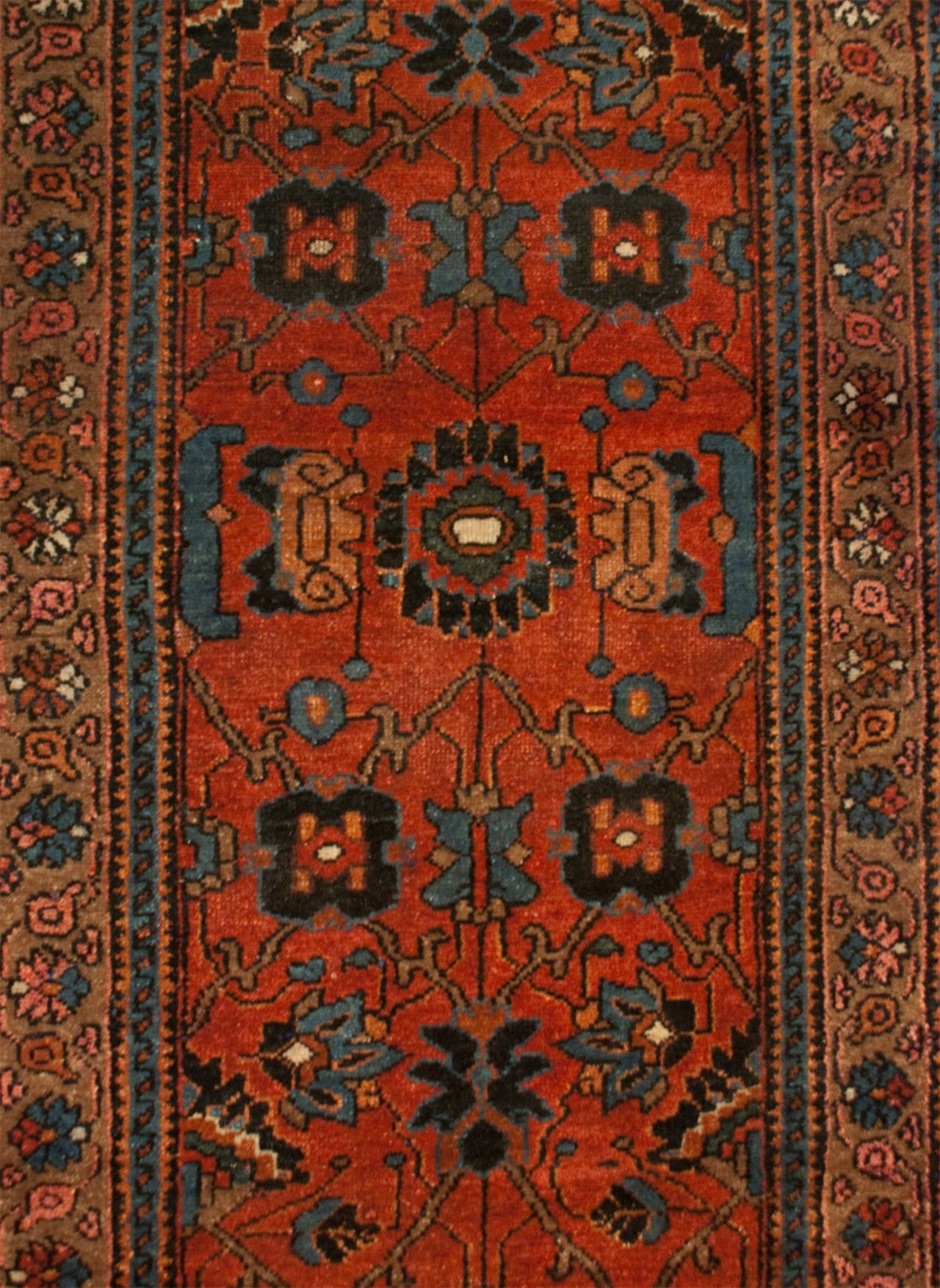 An early 20th century Persian Lilihan runner with an all-over floral pattern, on a rusty-carrot background, surrounded by a contrasting floral border.