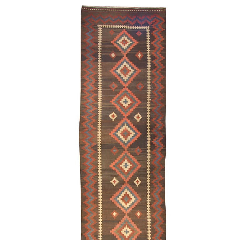 An early 20th century Persian Shahsevan kilim runner with ten multicolored diamond medallions on a natural wool background, surrounded by a wonderful red and indigo zig-zag border.