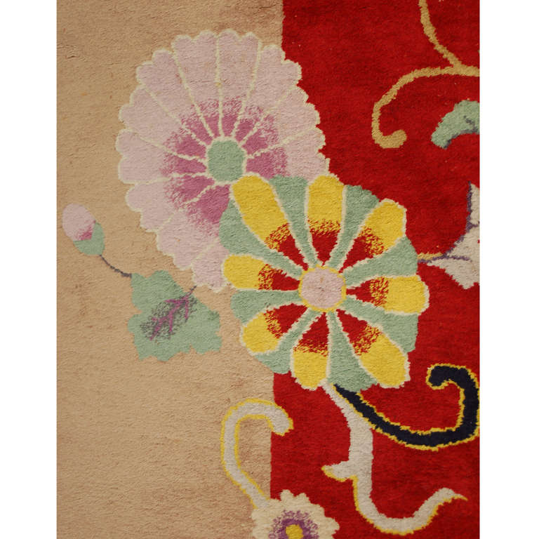 A wonderful Nichols Chinese Art Deco rug, circa 1920s, with a brilliant cranberry red background, with a beautifully rendered scrolling vines and floral pattern with a border surrounded by scholars' objects and potted flowers.