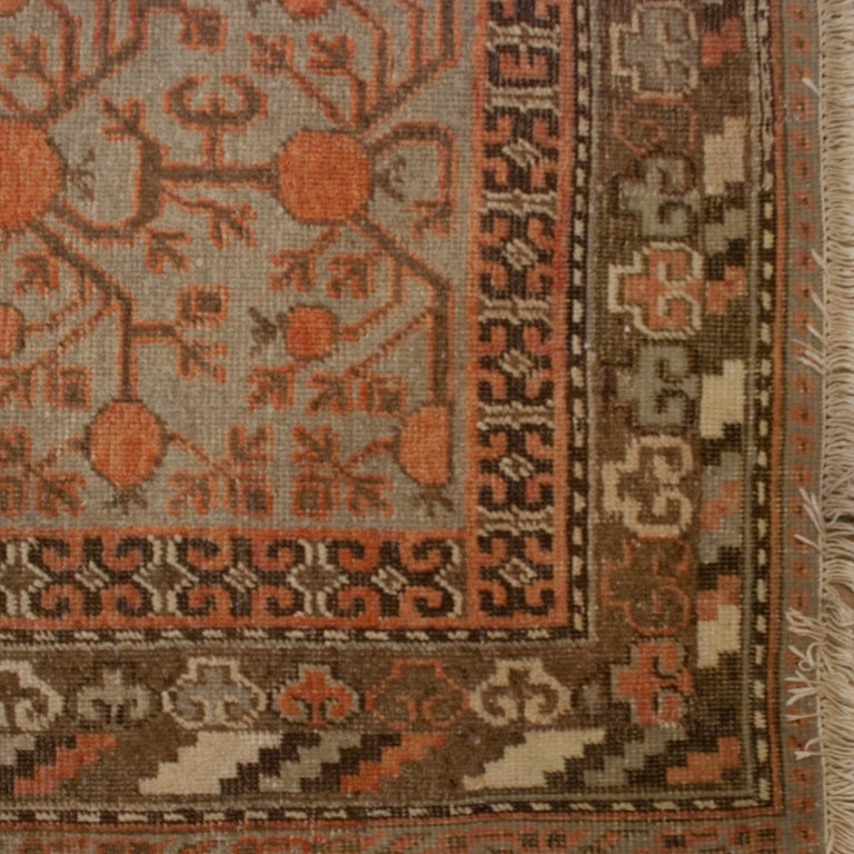 An early 20th century Central Asian Khotan carpet with pomegranate motif on a pale blue background surrounded by a contrasting border.

Measures: 5' x 9'8