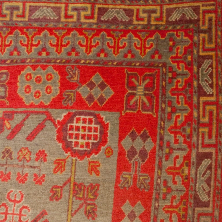 An early 20th century Central Asian Khotan carpet with unusual floral motif pattern on a pale blue background surrounded by contrasting crimson and violet floral border.

Measures: 6'3