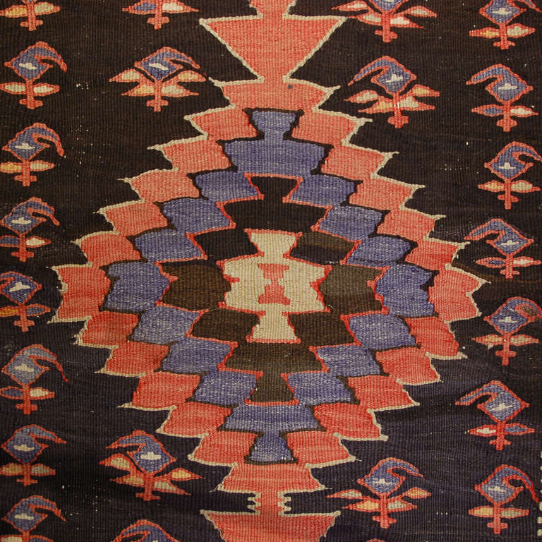 An early 20th century Persian Shahsevan Kilim runner with five multicolored diamond medallions amidst a field of paisleys, surrounded by a multicolored geometric pattern.
