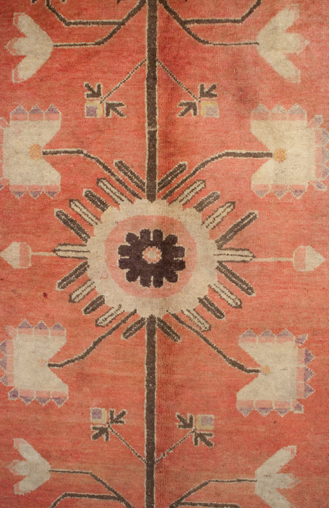 An early 20th century Central Asian pictorial Khotan rug depicting two vases with flowering peony branches, uniting in the center with one large central floral medallion, surrounded by a contrasting floral and leaf border.