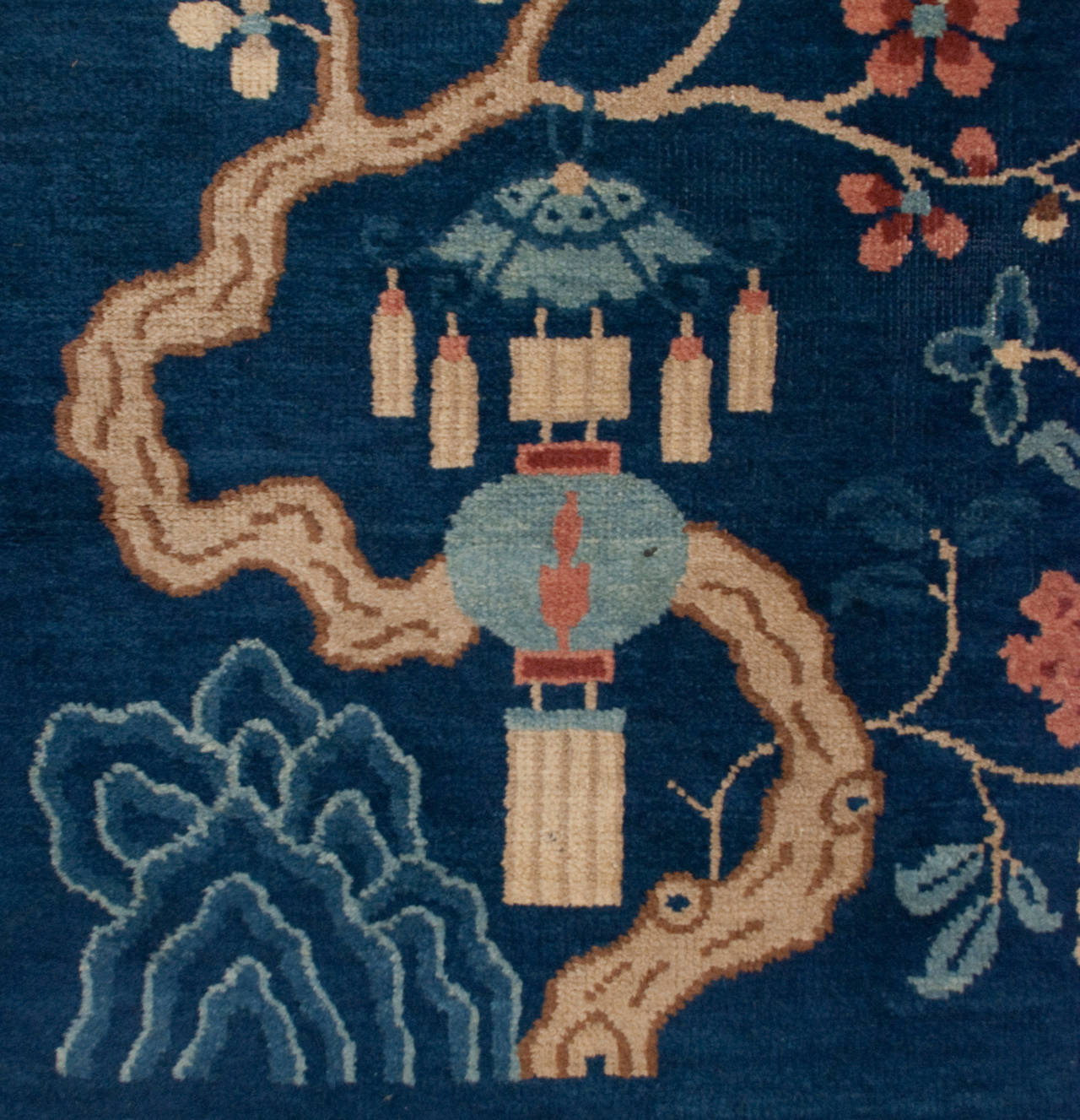 An unusual late 19th century Chinese Peking rug with a wonderful indigo ground and an asymmetrical flowering branch motif in one corner and a rising moon in the opposite corner.