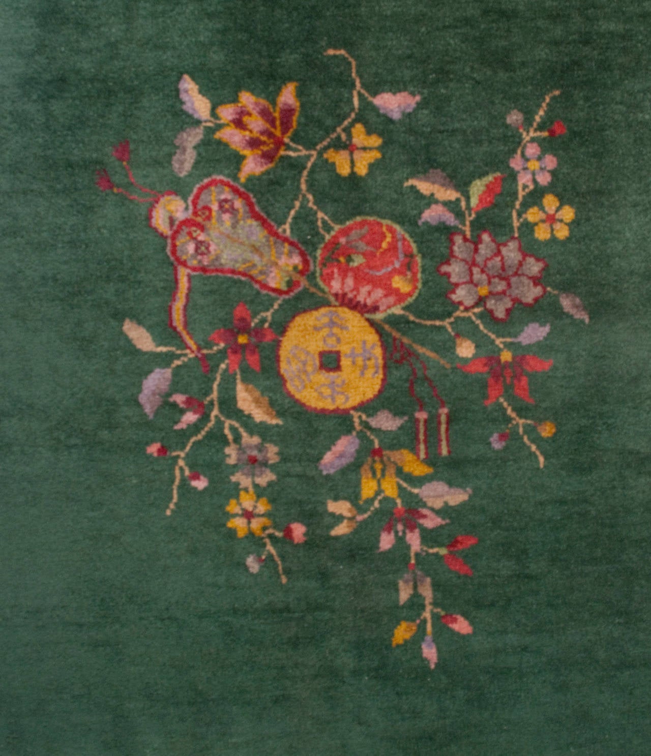 An early 20th century Chinese Art Deco rug with an emerald background surrounded by a multicolored flowering branched and a floral and garden pavilion landscape border.