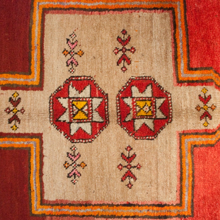 An early 20th century Turkish Anatolian carpet with three large central geometric medallions in a crimson background, surrounded by a multicolored leaf pattern border.

Measures: 5' x 10'5