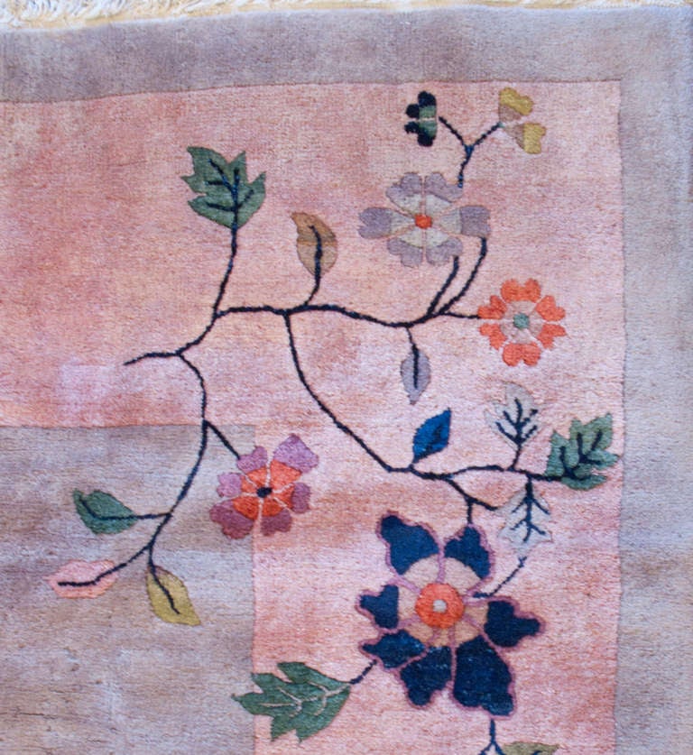 A wonderful early 20th century Chinese Art Deco rug with a taupe field surrounded by a wide pale pink border and an asymmetrical pattern of auspicious peonies, lotus, and cherry blossoms.
       