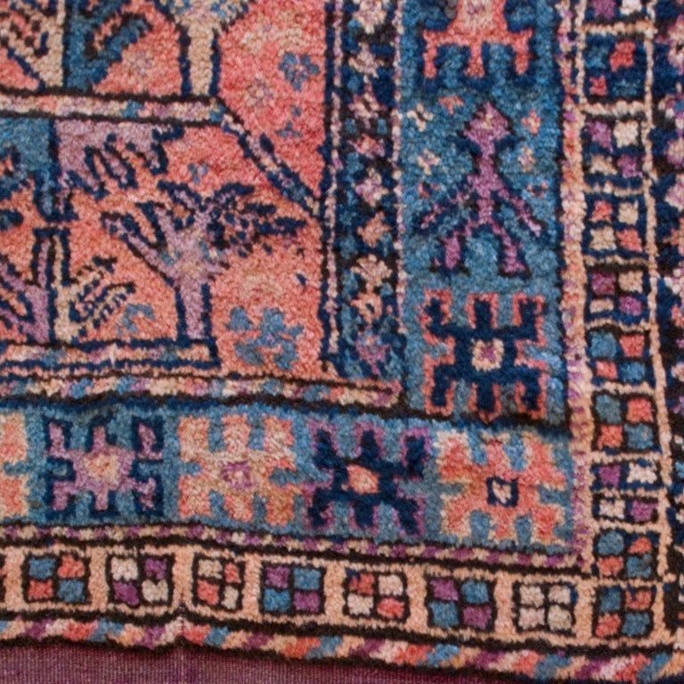 An early 20th century Balochi carpet with three narrow tree of life panels on an orange background, surrounded by a contrasting border, 4'8