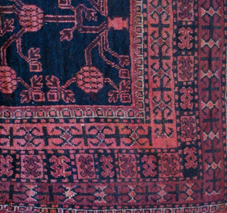 An early 20th century Central Asian Khotan carpet with an all-over pomegranate motif on an indigo background, surrounded by a complementary geometric border.

Measures: 4'3