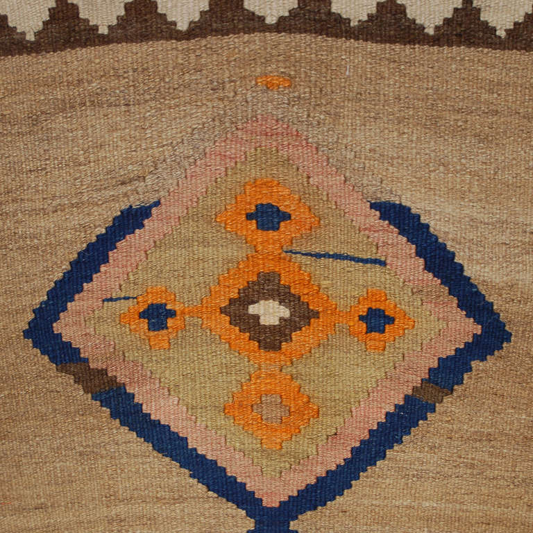 An early 20th century Persian Qazvin Kilim runner with ten diamond medallions on a natural wool background, surrounded by multiple contrasting geometric borders.