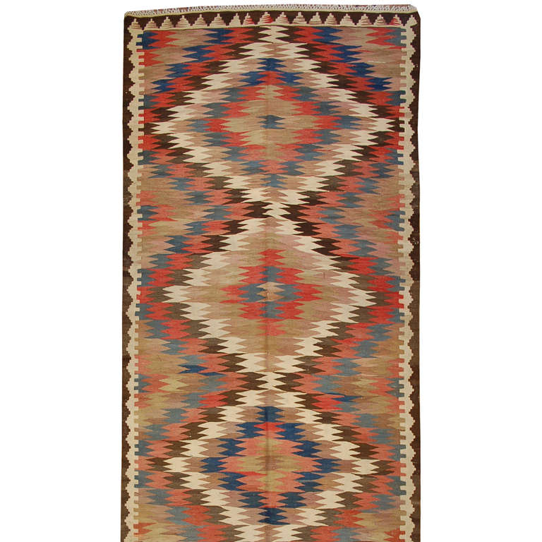 An early 20th century Persian Kilim runner with wonderful zigzag woven diamond pattern of alternating crimson, white, indigo and natural wool, surrounded by a complementary border.