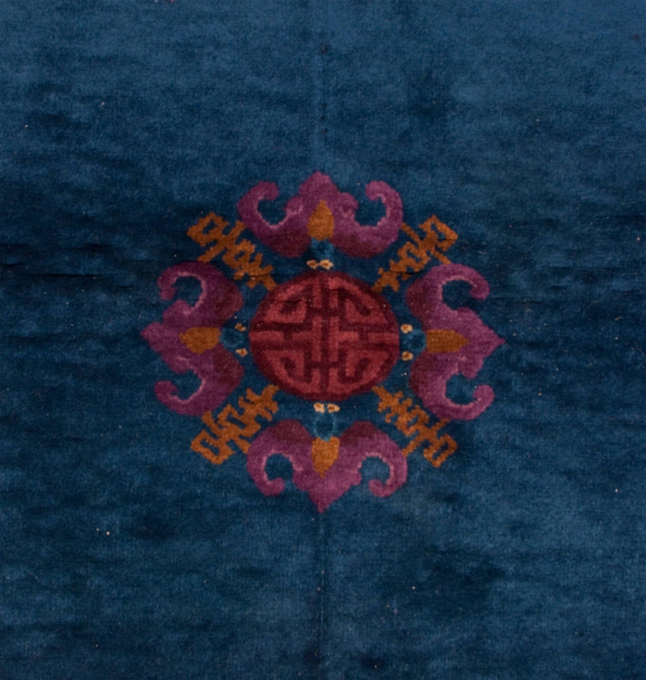 An early 20th century Chinese Art Deco rug with a beautiful indigo background surrounded by a complementary border with a pink, violet and indigo floral pattern.