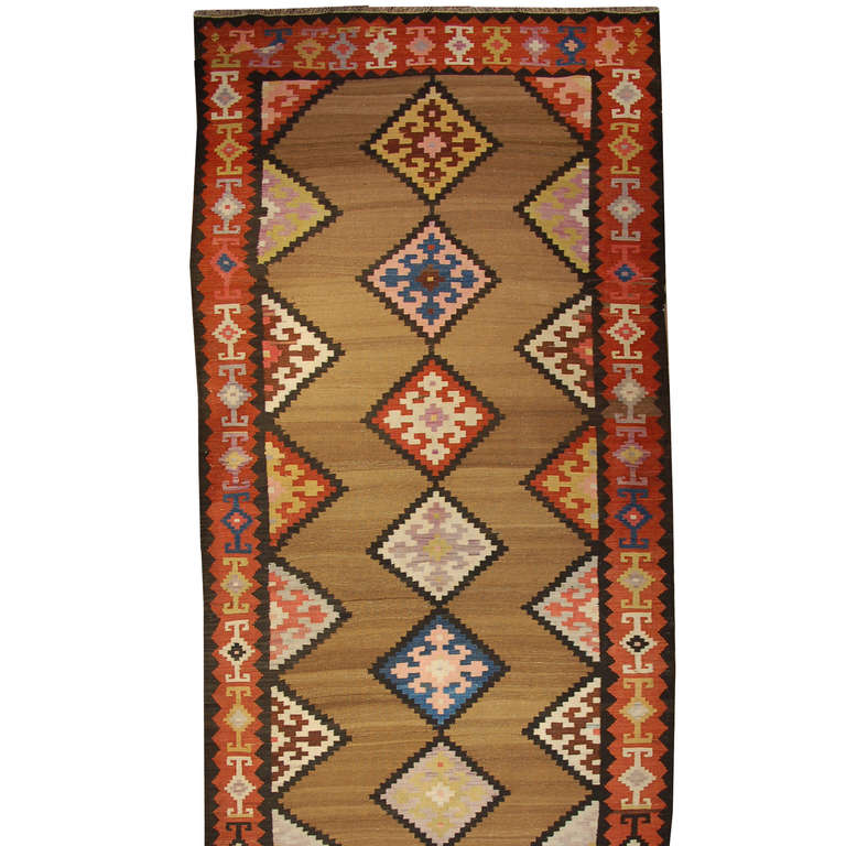 An antique, early 20th century, Persian Zarand Kilim runner with multiple diamond medallions on a natural wool background, surrounded by a contrasting geometric crimson border.