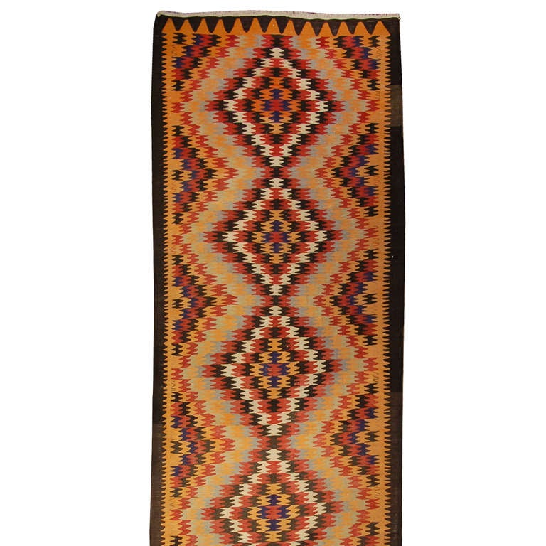 Tapis Ersari du début du XXe siècle, de style persan, présentant un brillant motif alterné de diamants en zigzag multicolores, entouré d'une simple bordure contrastée.