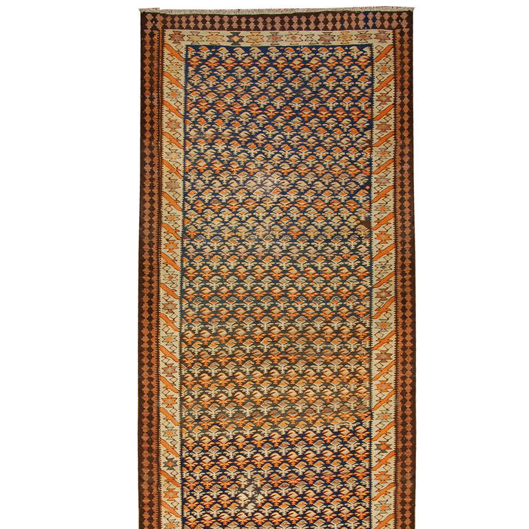 An early 20th century Persian Veramin Kilim runner with all-over paisley design on an indigo background, surrounded by multiple contrasting borders.