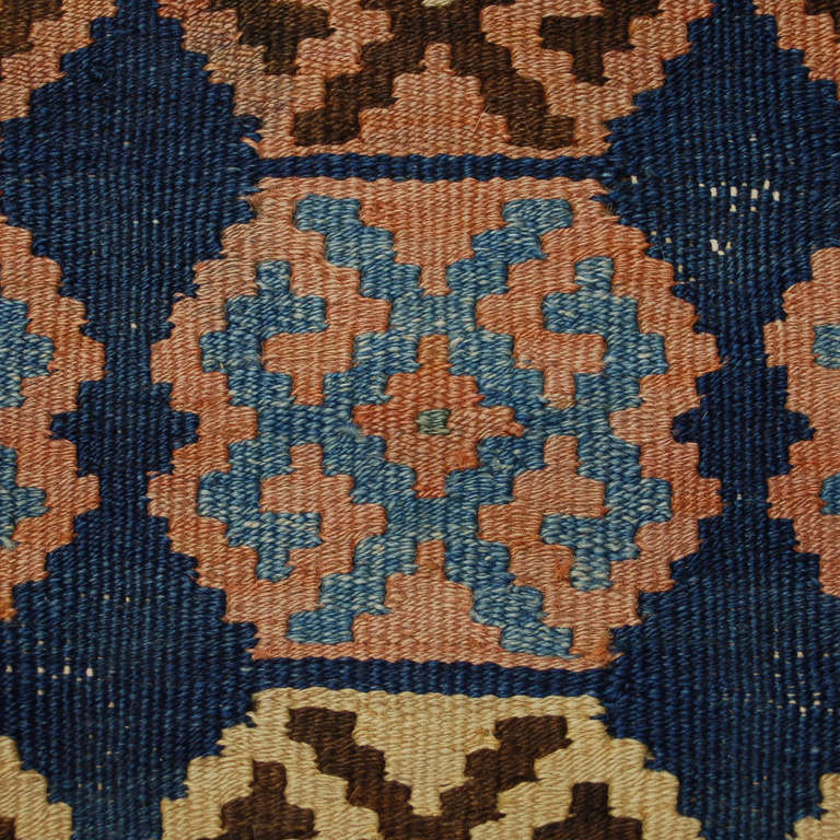 Ein antiker persischer Qazvin-Kilim-Läufer aus den 1930er Jahren mit einem mehrfarbigen, abwechselnden sechseckigen Streifenmuster auf indigoblauem Hintergrund, umgeben von einer kontrastierenden geometrischen Bordüre.