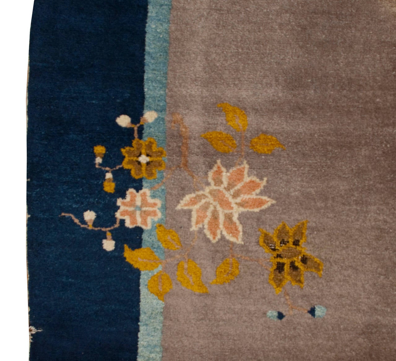 An early 20th century Chinese Peking rug with an asymmetrical floral pattern on a grey background, surrounded by a light and dark indigo border.