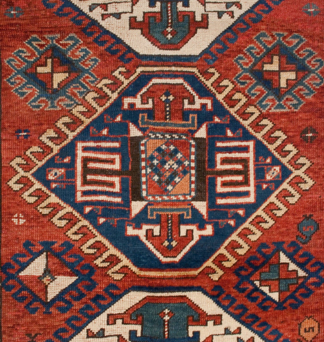 A late 19th century Persian Kazak rug with four wonderful diamond medallions on a crimson field of flowers with goats, surrounded by multiple complementary geometric borders.