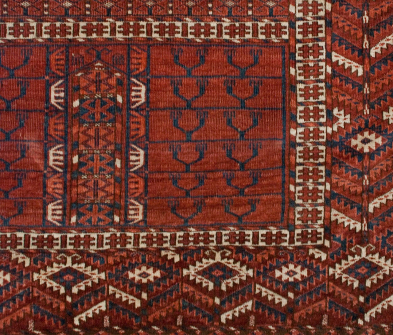 A late 19th century Persian Turkmen prayer rug with a wonderfully elaborate floral and geometric pattern surrounded by a complementary geometric border.