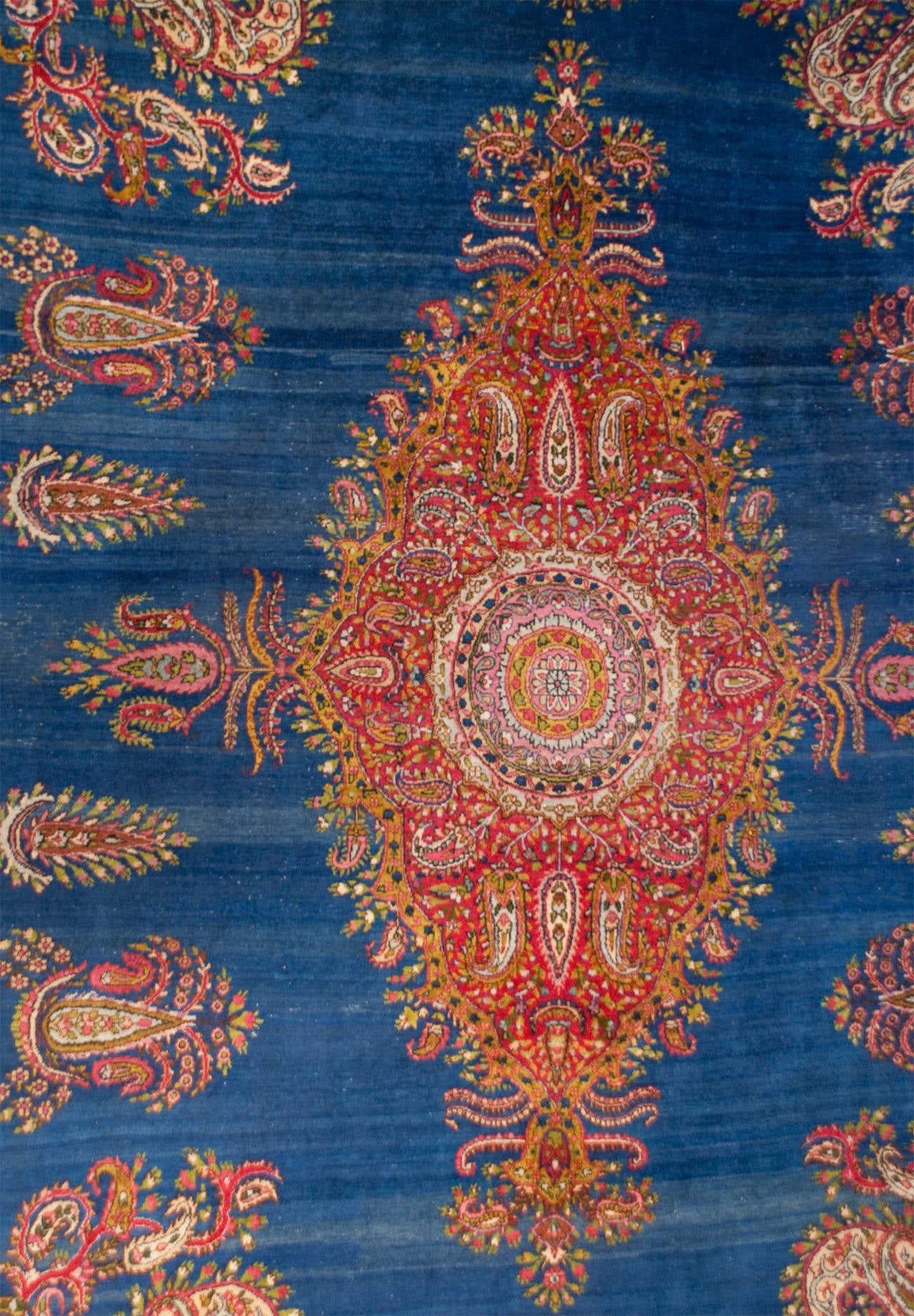 An early 20th century Persian Kirman rug with a wonderful indigo background, with a paisley pattern overlay, surrounded by multiple complementary floral and paisley borders.