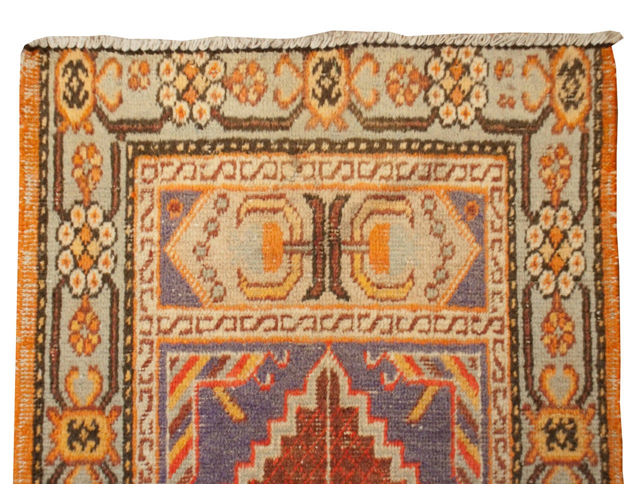 An early 20th century Central Asian Khotan prayer rug with a beautiful floral border surrounding a central crimson geometric field.