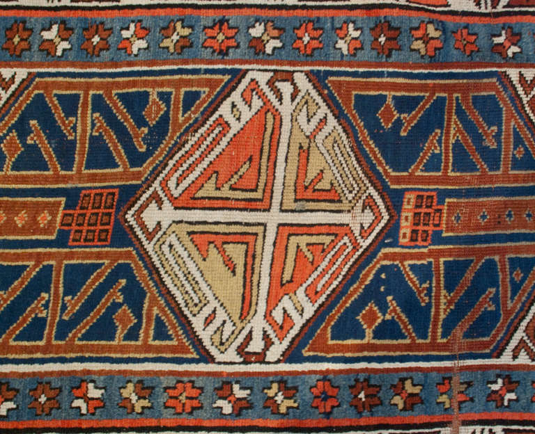 Un étonnant tapis persan Kazak de la fin du 19e siècle avec un merveilleux motif géométrique sur un fond indigo, entouré de multiples bordures florales et géométriques contrastantes.