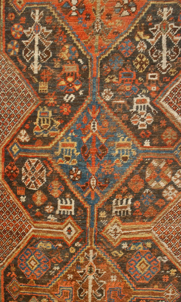 A beautiful 19th century Persian Qashqai runner with multiple central diamond medallions amidst a field of flowers, surrounded by multiple complementary geometric borders.
