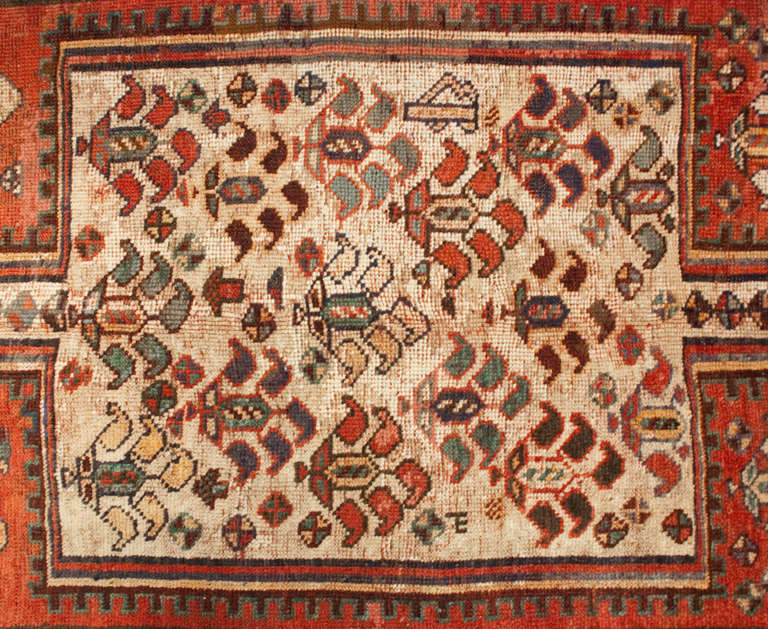 An early 20th century Persian Kurdish rug with central rectangular field of flowers medallion on a crimson background, surrounded by multiple contrasting geometric floral borders.
