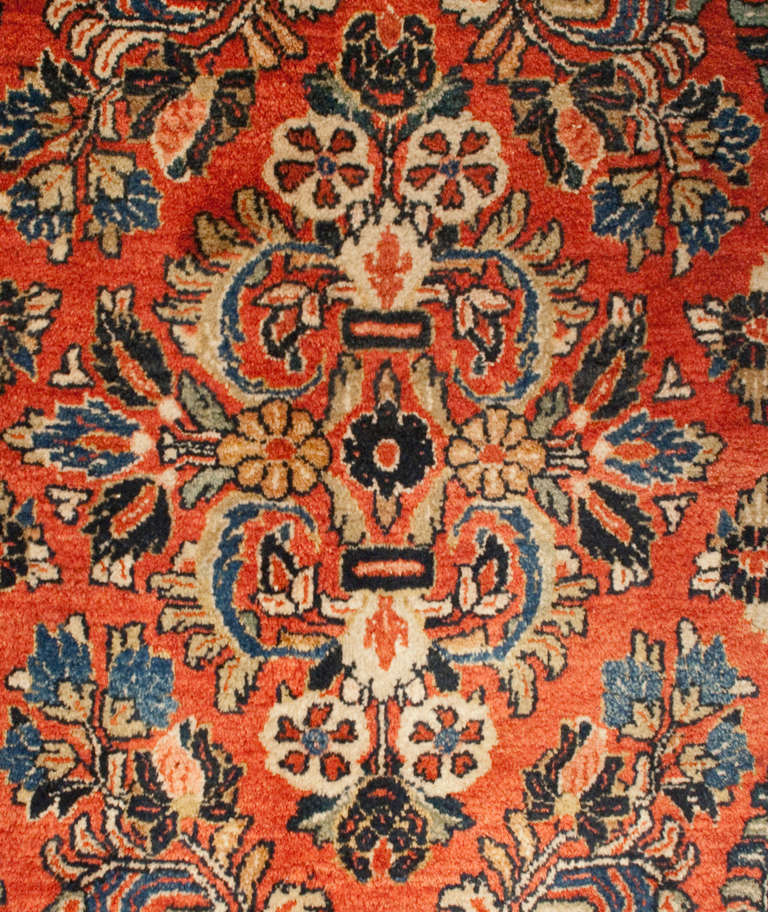 Un runner Sarouk persiano dei primi del Novecento con motivo floreale all-over su sfondo color ruggine, circondato da un bordo floreale complementare.