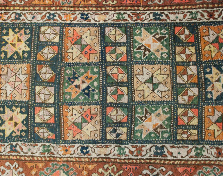 An early 20th century Persian Kurdish runner with multiple geometric floral medallions surrounded by wonderful wide complementary floral borders.