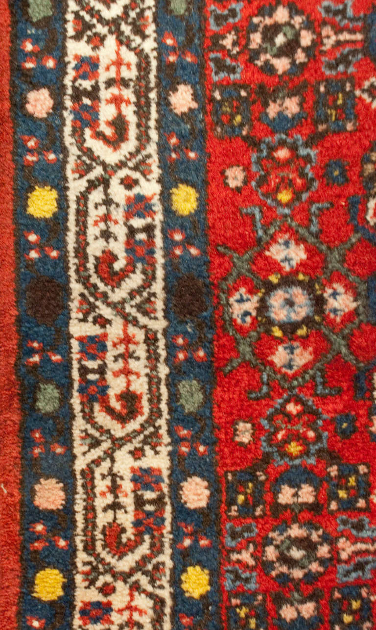 An early 20th century Persian Hossein Abad runner with all-over geometric and floral pattern on a crimson background, surrounded by multiple floral borders.
