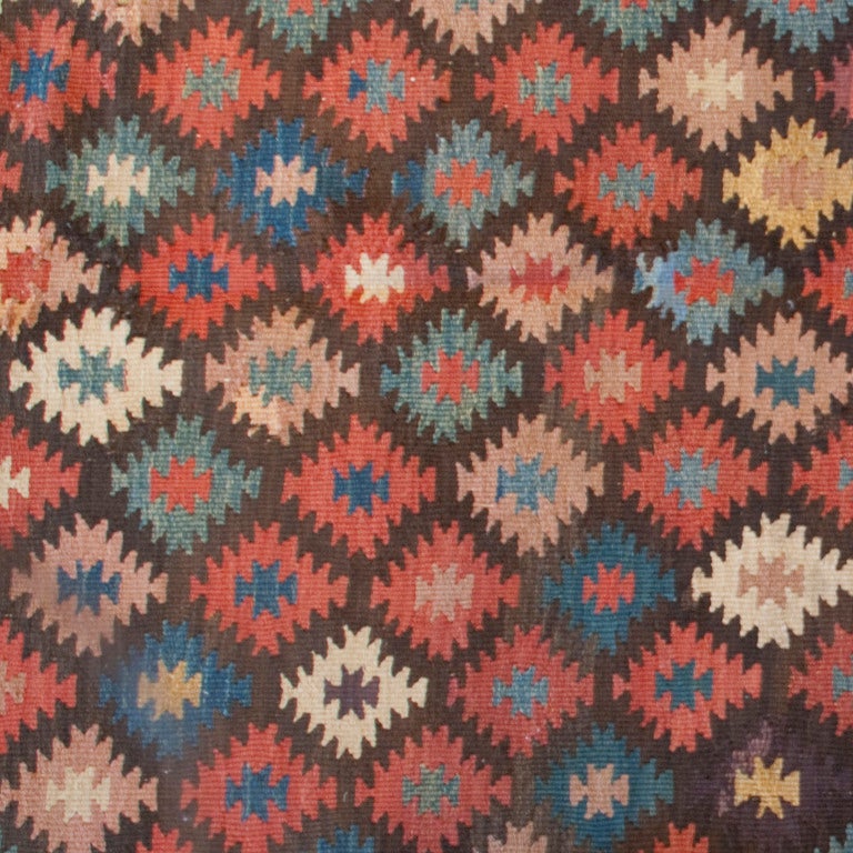 An early 20th century Persian Azari Kilim carpet with multicolored diamond field surrounded by a layered vine and tree motif border.



Measures: 14'3