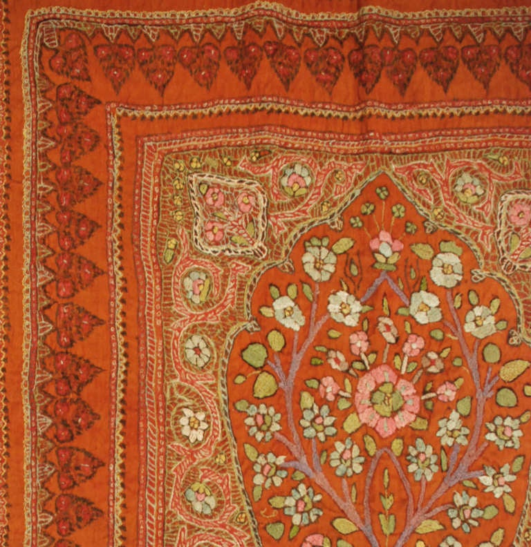 Un textile ancien en soie brodé Kirman Suzani avec deux arbres de vie entrelacés avec des branches fleuries entourées d'une bordure complémentaire.

Mesures : 2'11