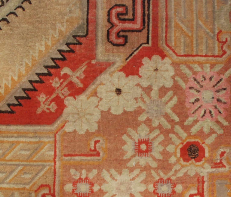 Un antique tapis Khotan d'Asie centrale avec un médaillon floral central entouré d'un motif floral géométrique.

Mesures : 5'6