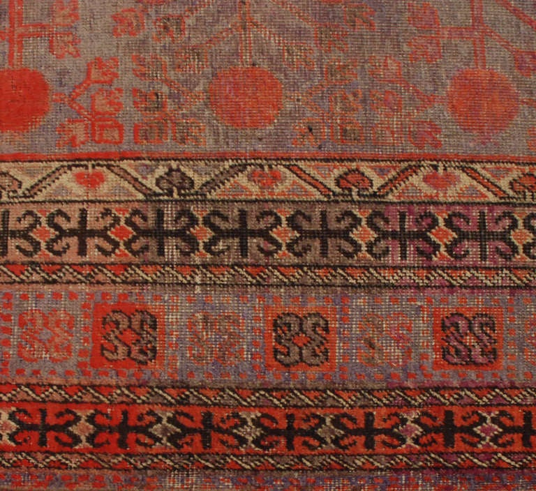 An antique, early 20th century, Central Asian Khotan rug with all-over pomegranate pattern on a pale indigo background surrounded by multiple complementary floral and geometric borders.

Measures: 6'2