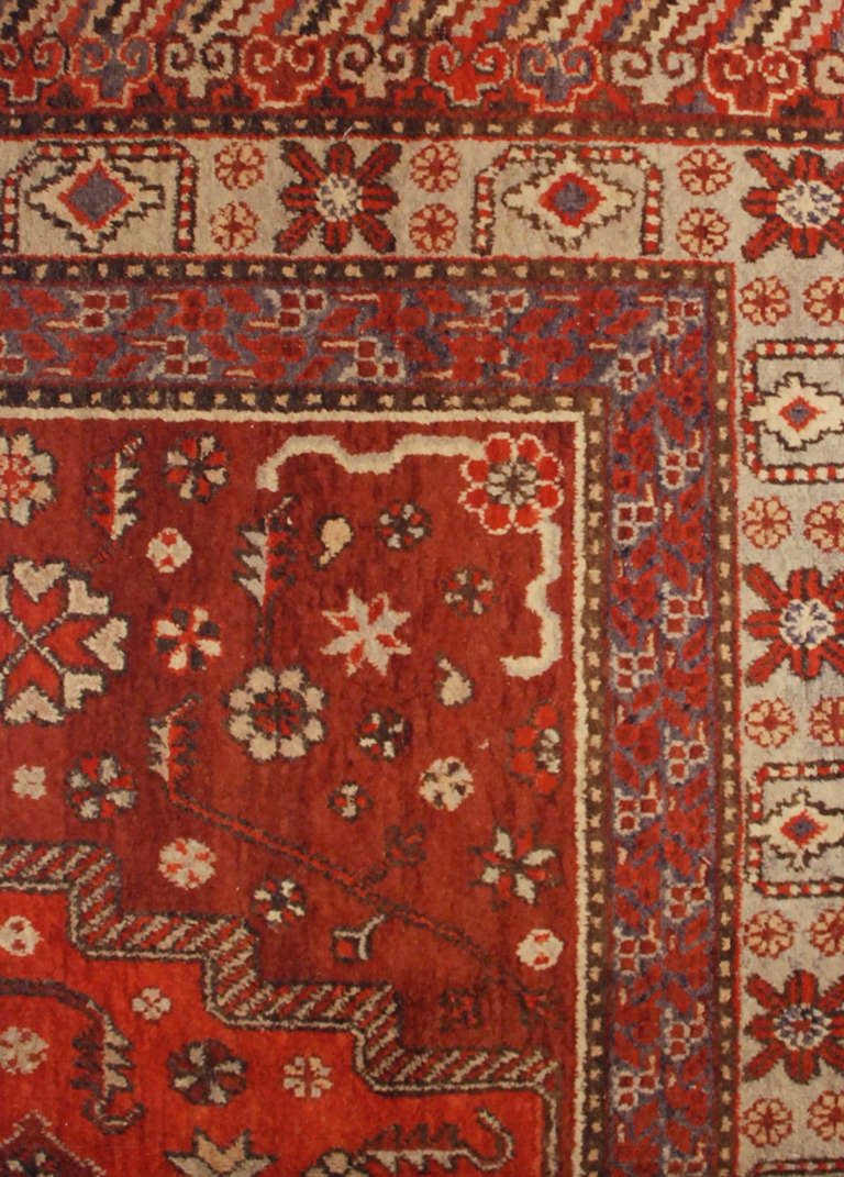 An antique, early 20th century, central Asian Samarkand rug with unusual diamond medallion amidst a field of flowers on a crimson background, surrounded by multiple contrasting floral borders.

Measure: 6'2