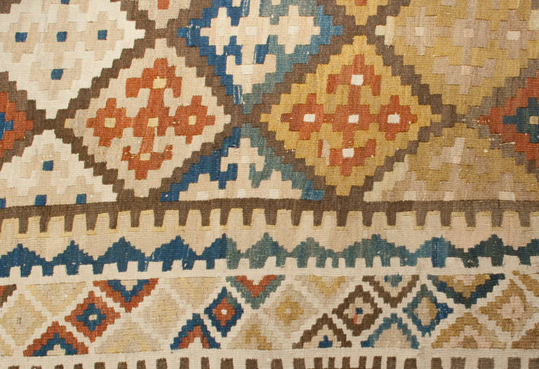 Runner persiano Shiraz Kilim dei primi del Novecento con motivo geometrico e a rombi multicolore all-over circondato da un bordo geometrico complementare.