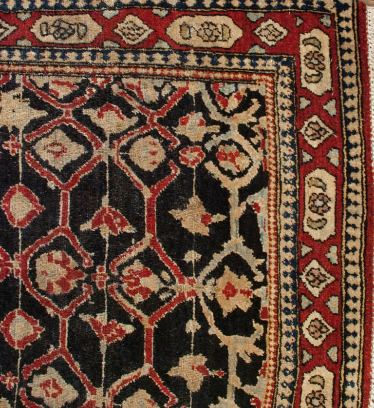 An early 20th century Persian Isfahan runner with intricately woven floral lattice pattern on a black background, surrounded by a contrasting floral border.