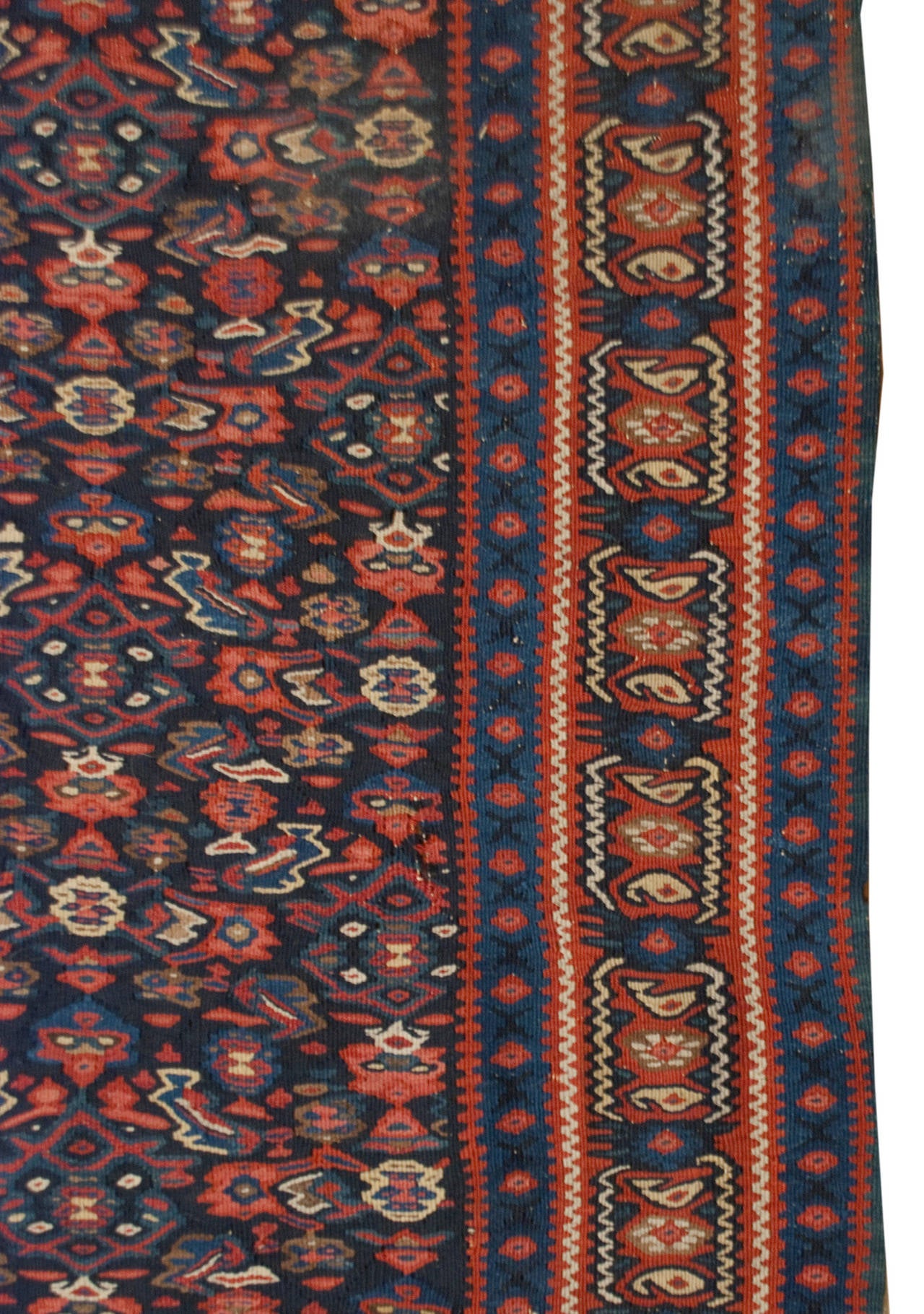 An early 20th century Persian Senneh rug with a beautiful all-over crimson and indigo field, surrounded by multiple complementary geometric and floral border.