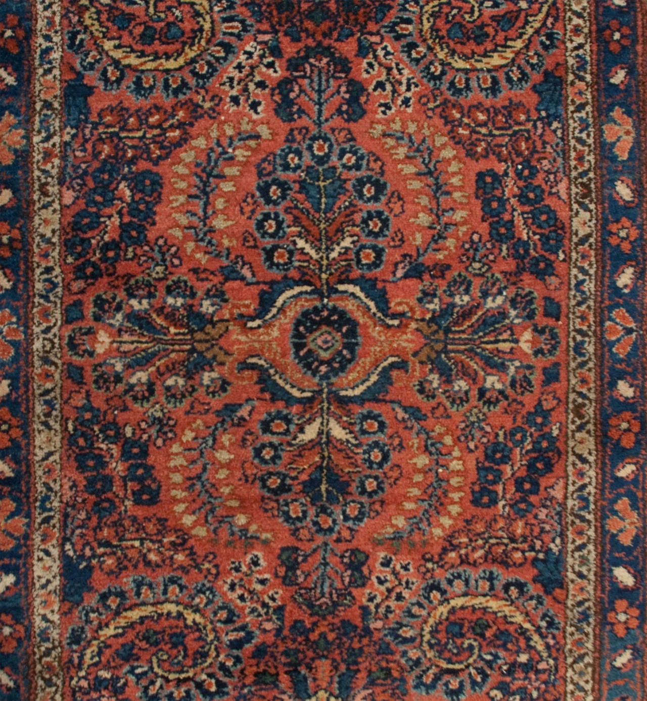 An early 20th century Persian Lilihan runner with a beautiful symmetrical multicolored tree-of-life pattern on a ruby background, surrounded by a complementary floral border.