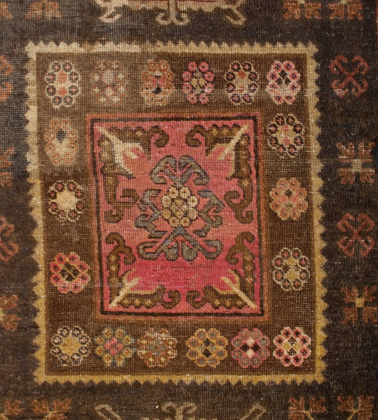 An early 20th century Central Asian Khotan rug with three central medallions, two circular and one square on a natural un-dyed background, surrounded by multiple contrasting geometric borders.